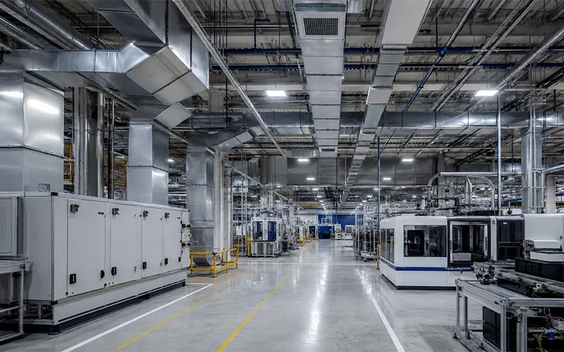 Fabbrica moderna con sistema di aerazione e filtraggio a soffitto e macchinari a pavimento.