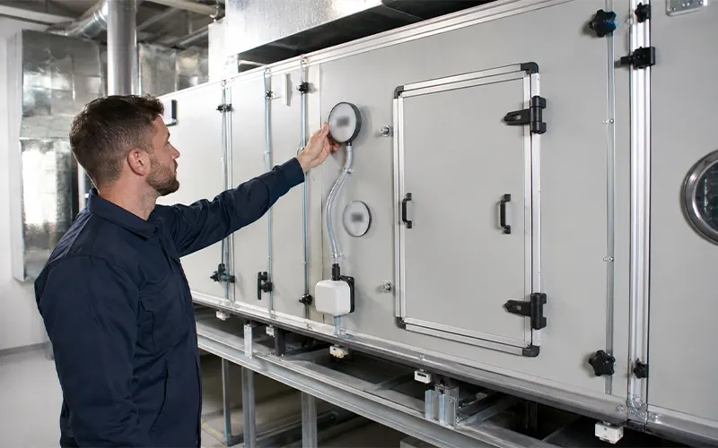 Tecnico che controlla il manometro della pressione differenziale in un sistema HVAC